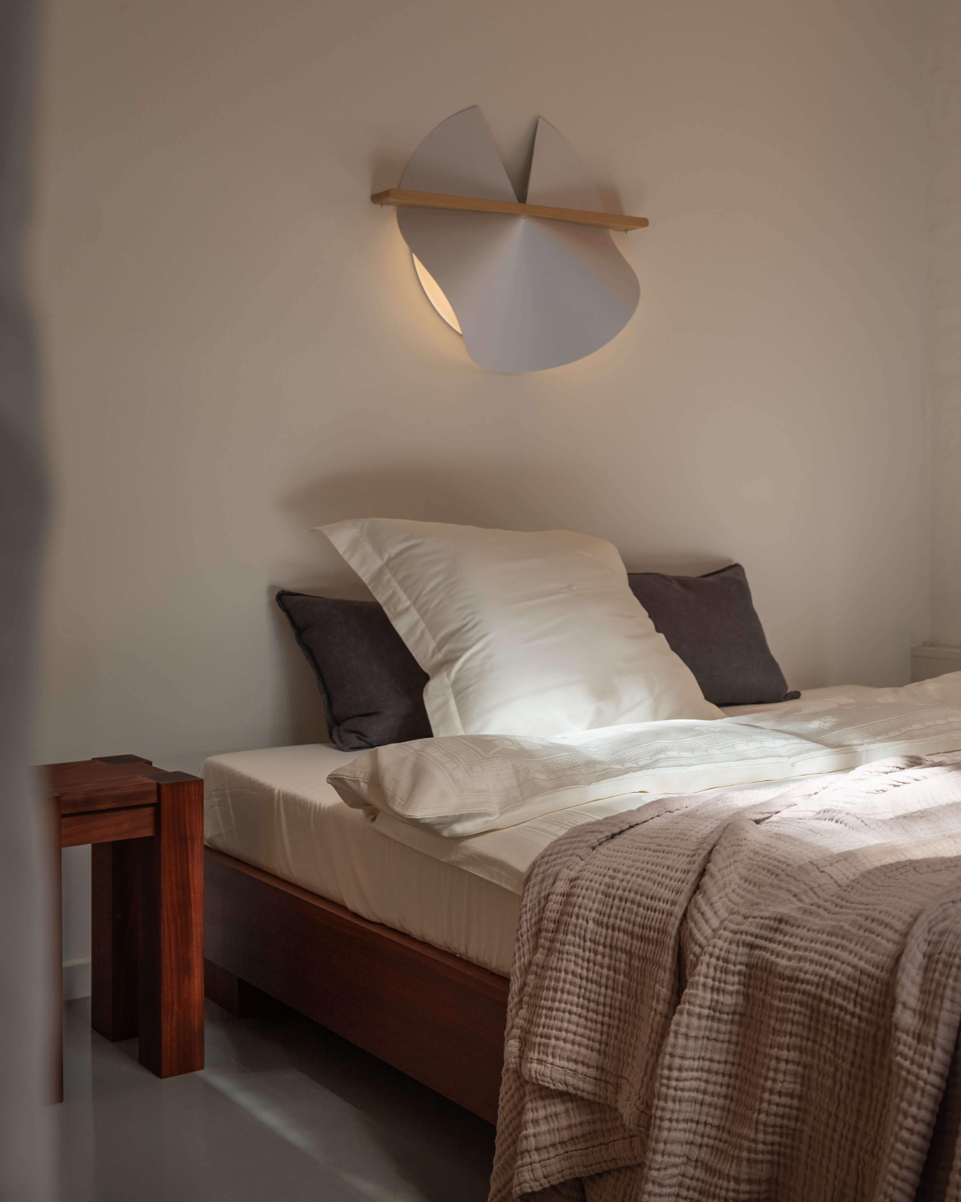 Dawn wall lamp in washi paper and oak, styled above a bed in a bedroom interior by Motarasu