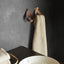 Two coat hooks on a wall, one empty and the other holding a towel