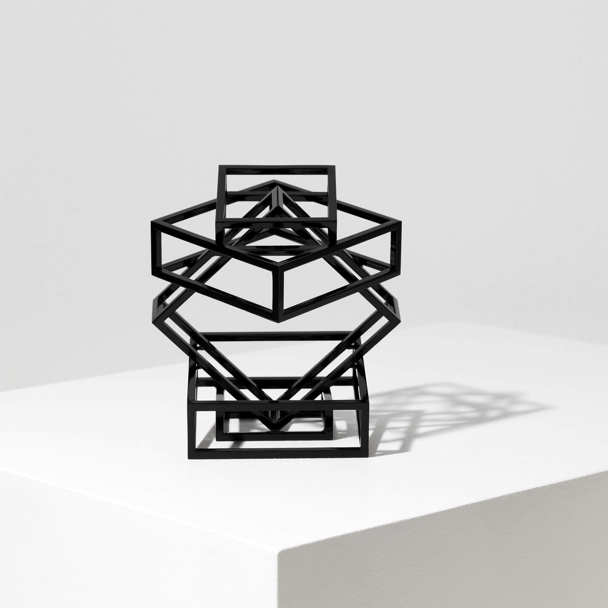 Steel sculpture on a flat surface, against a white background