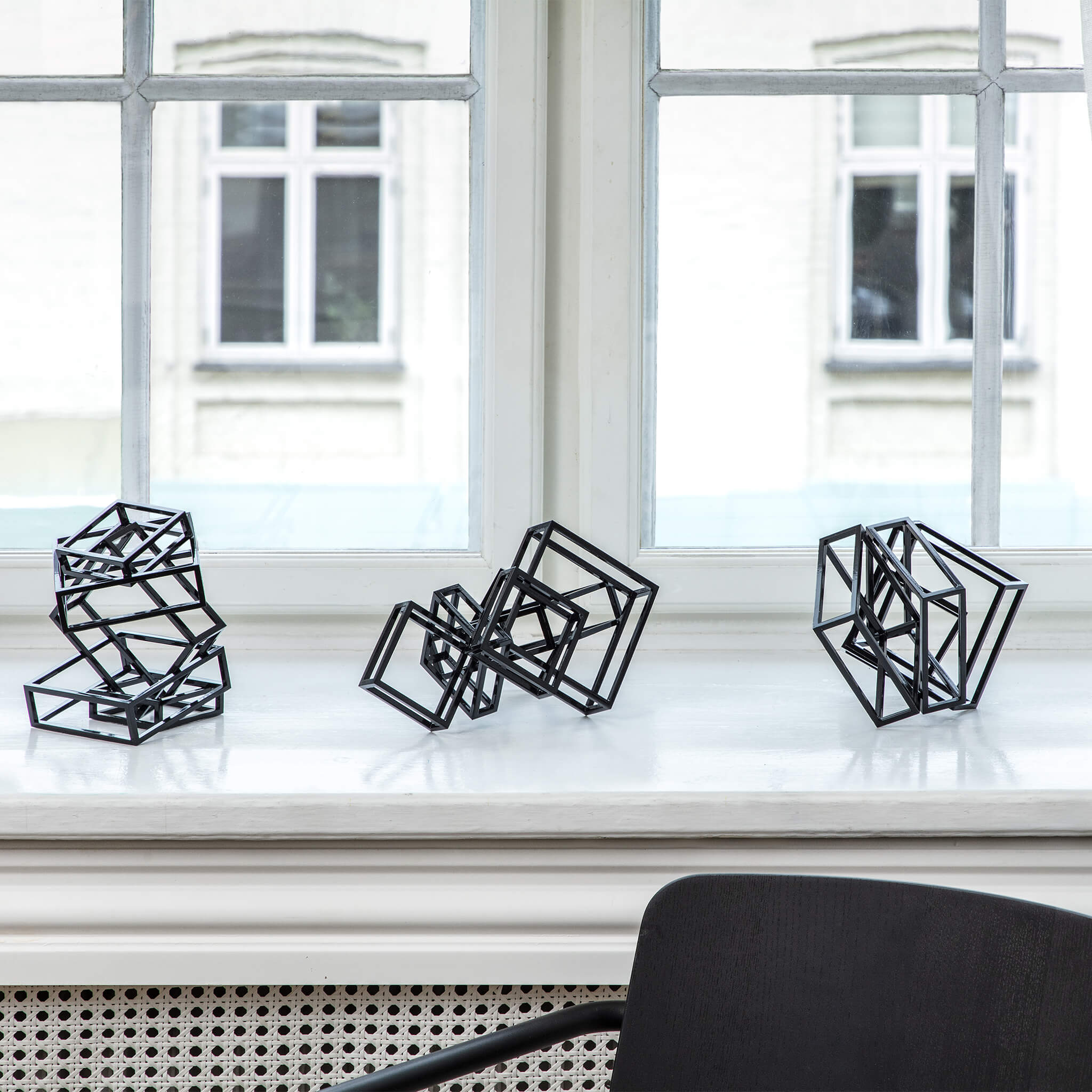 Collection of three steel sculptures, coated in black, placed on a window seal