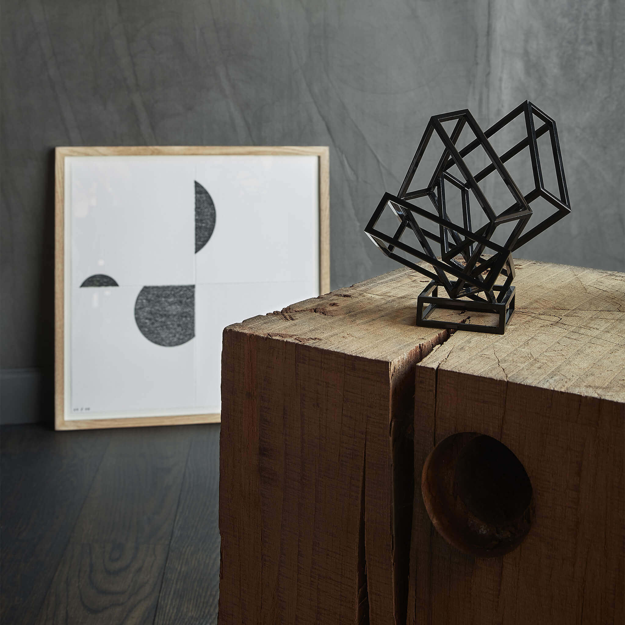 Black coated steel sculpture placed in front of a painting