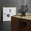 Black coated steel sculpture placed in front of a painting
