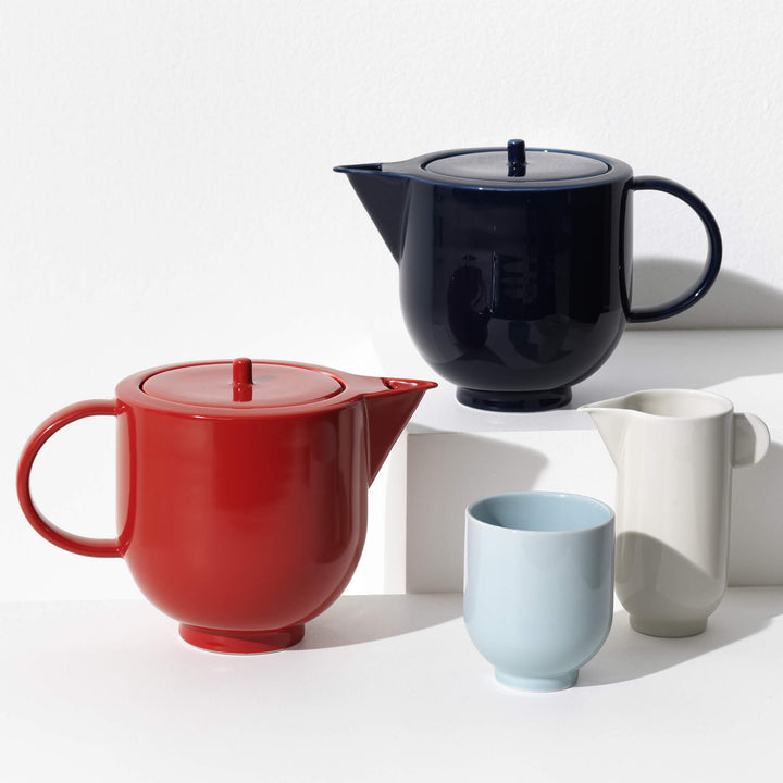 Close up of porcelain tea set featuring two teapots, one pitcher and one mug