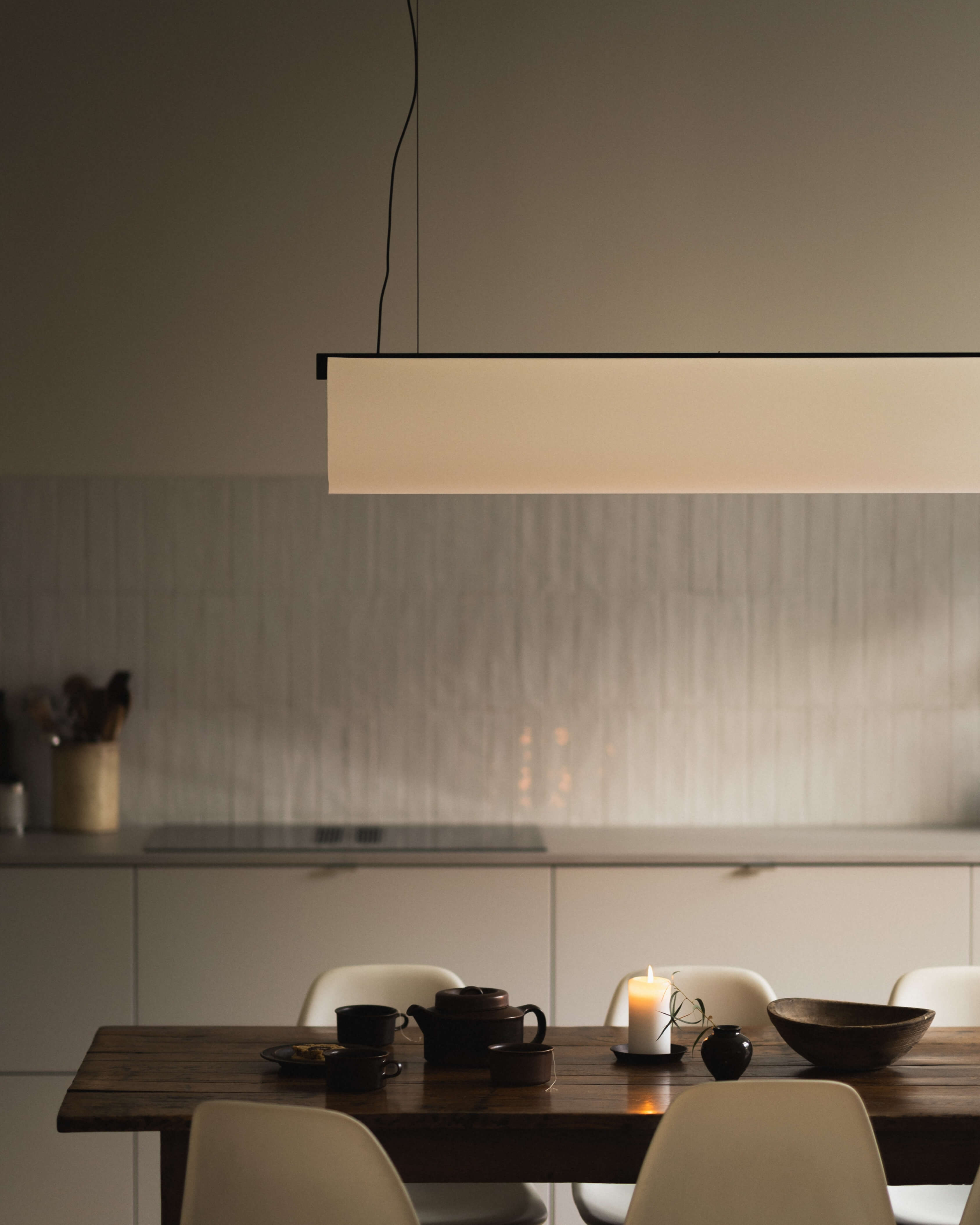 Enso Pendant in washi paper and oak with black finish, styled above a dining table in a minimalist interior by Motarasu