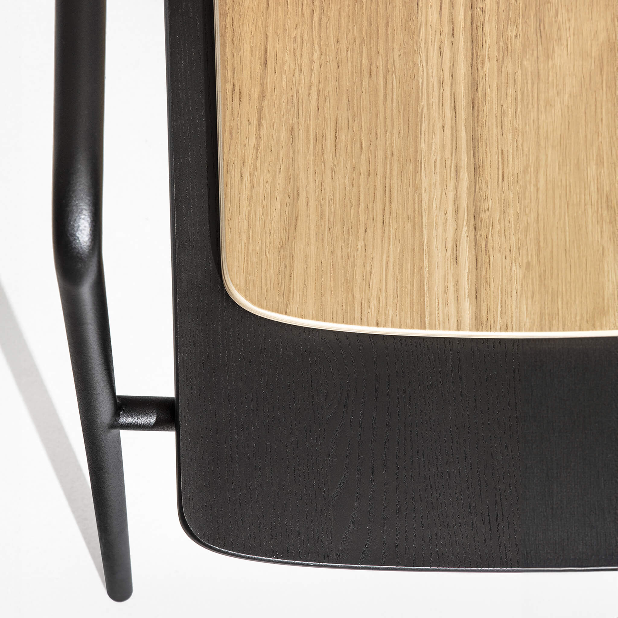 Two dining chairs stacked together for comparison, black and natural oak version