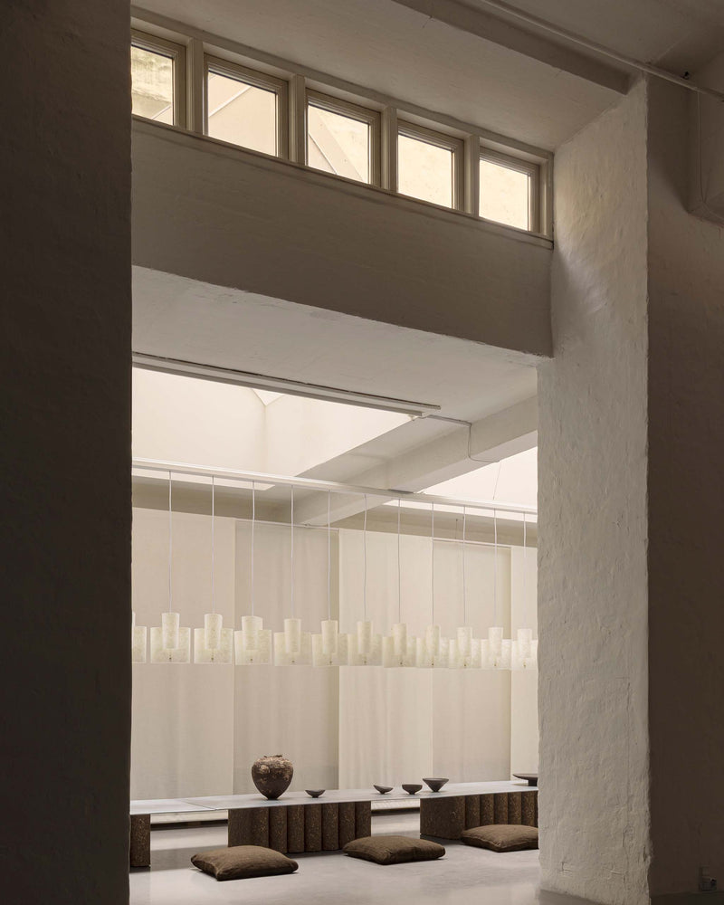 A minimalist interior space with a line of Sekiun 23 Raw hanging in a long line to shape the room