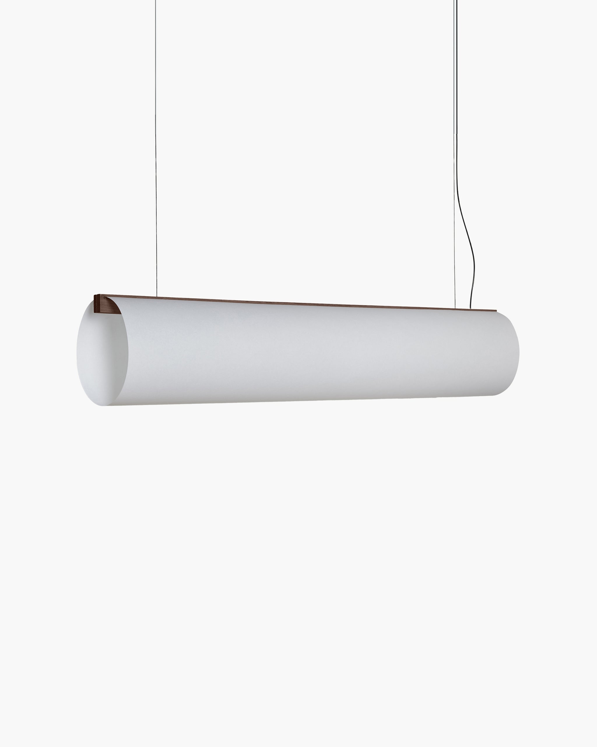 A modern cylindrical pendant light fixture in matte white, suspended by thin black cords against a solid white background.