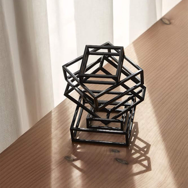 Black coated steel sculpture placed on a wooden surface