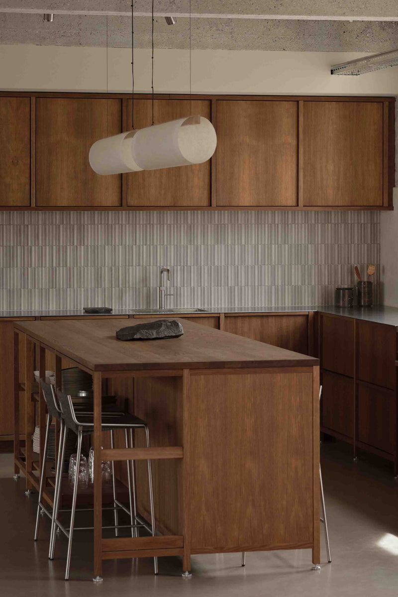 A modern wooden kitchen interior from Vermalnd featuring a central wooden island, with our tactile Enso Raw hanging above the island