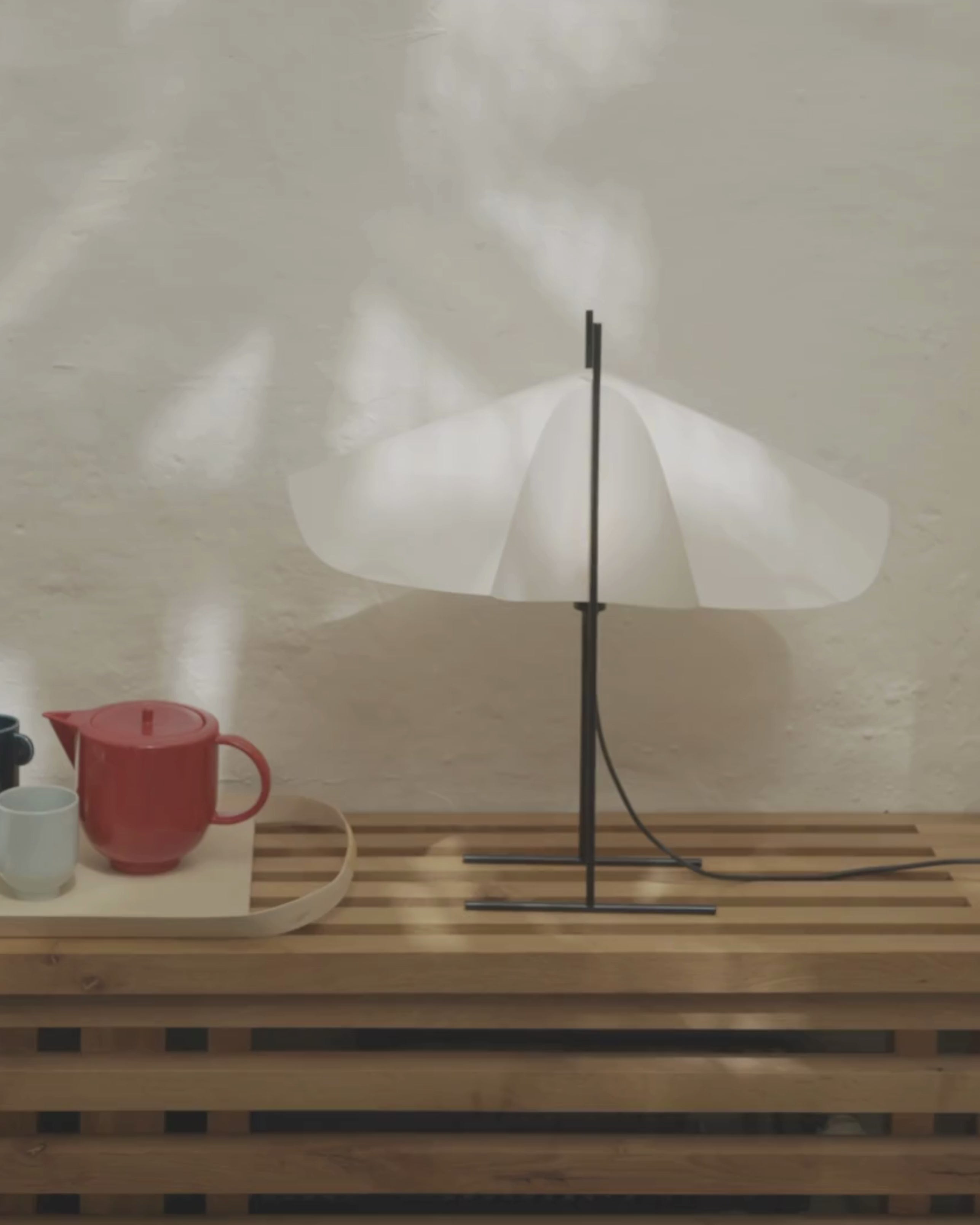 Cho floor lamp in translucent PVC with black steel base and light off, animated view of wing silhouette placed in interior setting with teapot next to it by Motarasu
