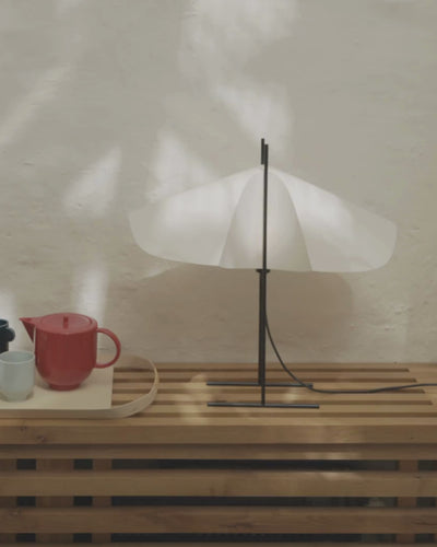 Cho floor lamp in translucent PVC with black steel base and light off, animated view of wing silhouette placed in interior setting with teapot next to it by Motarasu